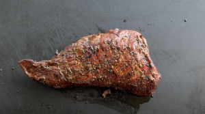 Perfectly grilled coffee-marinated tri-tip resting on the grill, uncut.