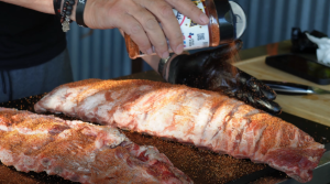 Seasoning ribs with rib rub, spreading evenly across the meat.