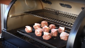 Bacon-topped meatballs cooking on a Z Grills pellet grill with an open lid.