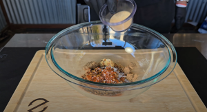 Pouring granulated sugar into a mixing bowl with other ingredients for pecan pie filling on a Z Grills cutting board.