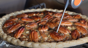 Checking the temperature of a freshly grilled pecan pie with a digital thermometer.