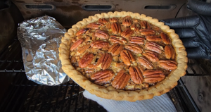 A freshly baked pecan pie cooling on a grill, showcasing a crispy crust and a rich pecan topping.