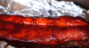 Close-up of a succulent, juicy rack of ribs slathered in a shiny, spicy BBQ sauce, showing off the perfect caramelization and seasoning.