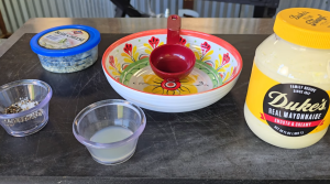 Ingredients for homemade blue cheese dressing laid out on a prep surface, including mayonnaise, lemon juice, black pepper, and crumbled blue cheese.