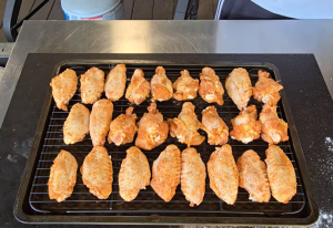 Seasoned chicken wings arranged on a wire rack, resting before being smoked on a pellet grill.