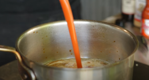 Buffalo sauce being poured into a saucepan during the cooking process.