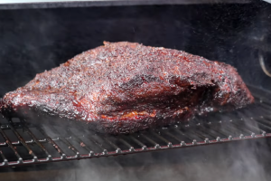 Smoked brisket developing a deep bark on a Z Grills pellet smoker with cherry wood pellets.