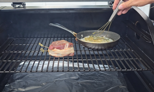 Bacon-wrapped filet and garlic butter pan cooking on the top rack of a Z Grills pellet grill