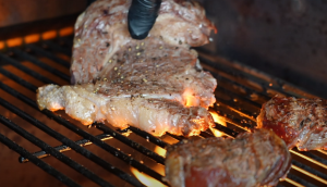 Searing ribeye and filet mignon steaks over open flame on a Z Grills pellet grill.