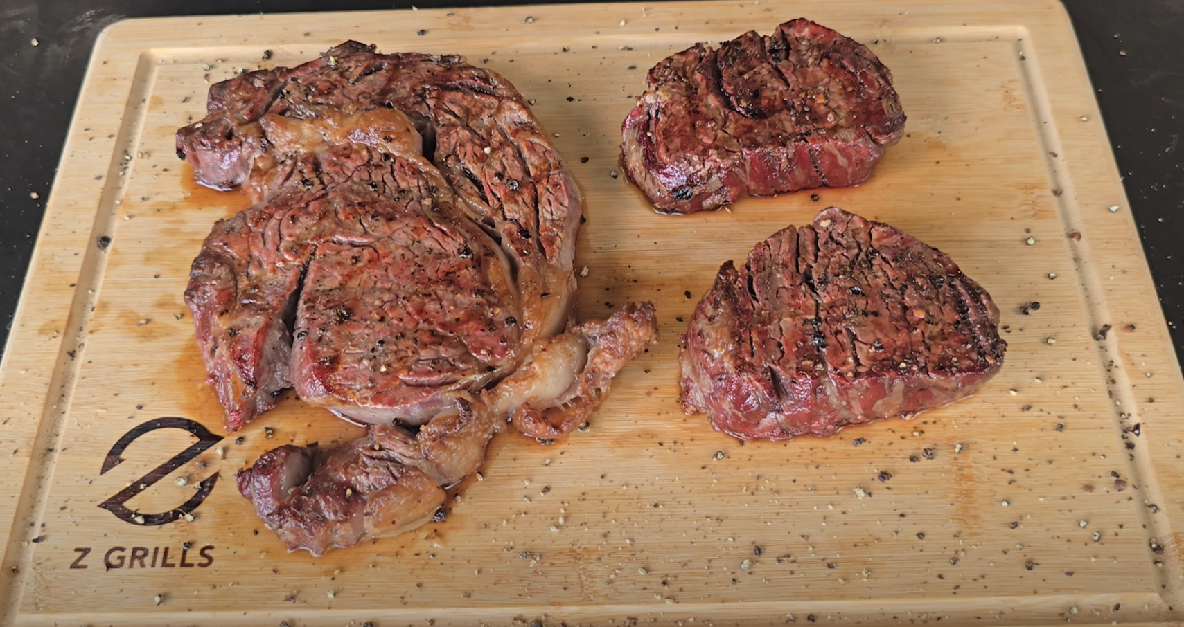 Cooked ribeye and filet mignon steaks resting on a Z Grills cutting board after searing.